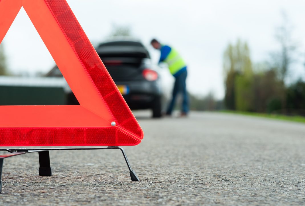 Warning triangle on the road with a roadside crew behind